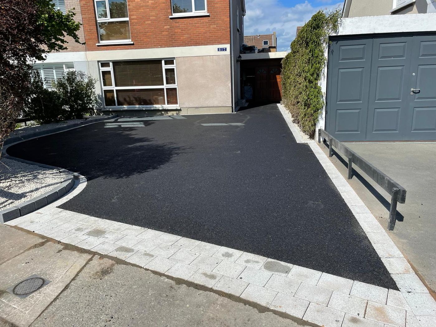 New tarmac driveway with a granite paving border